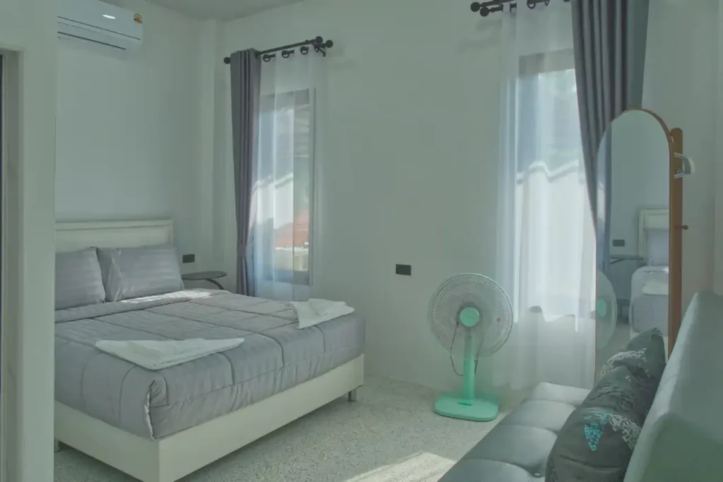 Bedroom 3 at Baan Bahng Can Do Krabi homestay with queen bed, sofa bed, two garden-view windows with grey curtains, floor fan, air conditioning, and full-length mirror