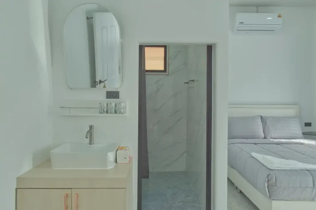En-suite bathroom entrance and vanity in Bedroom 3 at Baan Bahng Can Do Krabi homestay, with vessel sink, marble-effect shower room, wall mirror, and queen bed alongside