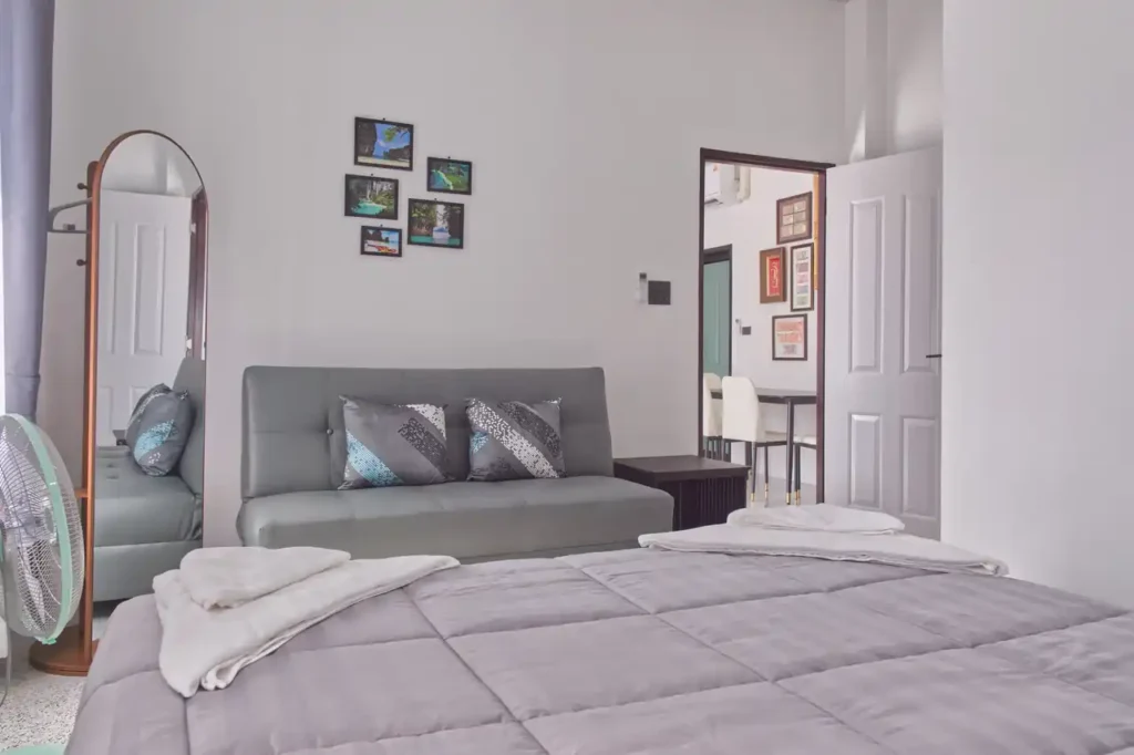 Bedroom 3 at Baan Bahng Can Do Krabi homestay with queen bed, sofa bed, full-length mirror, Krabi nature photo prints, floor fan, and open door to shared living area