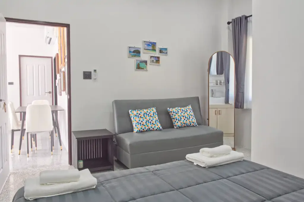 Bedroom 4 at Baan Bahng Can Do Krabi homestay showing queen bed, sofa bed with colourful cushions, Krabi island photo prints, full-length mirror, and open door to dining area